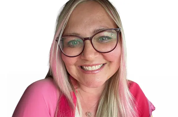 Smiling woman with glasses and pink streaked hair.
