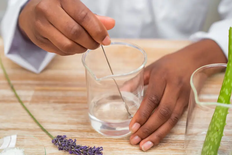 Mixing liquid in beaker with lavender and aloe